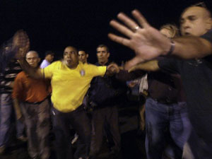 Dos hombres intentan impedir ataque contra un reportero de AP (segundo desde la derecha, con el rostro tapado) cuando una turba acechó anoche a los periodistas en el Malecón habanero. Foto de AP