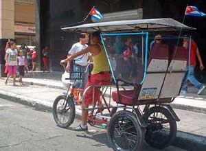 Bicitaxi patriótico por la céntrica avenida de Galiano en La Habana. 